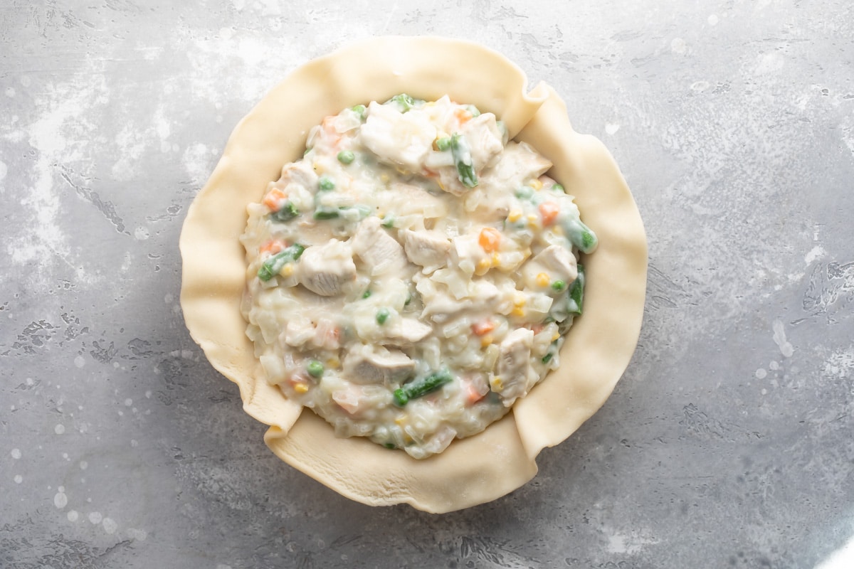Unbaked pie crust with chicken pot pie filling inside.