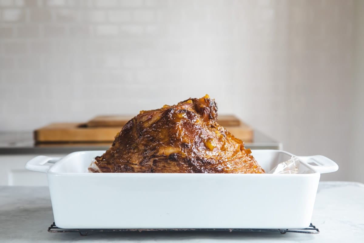 A glazed ham in a baking dish.