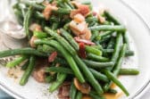 A platter full of green beans and bacon.