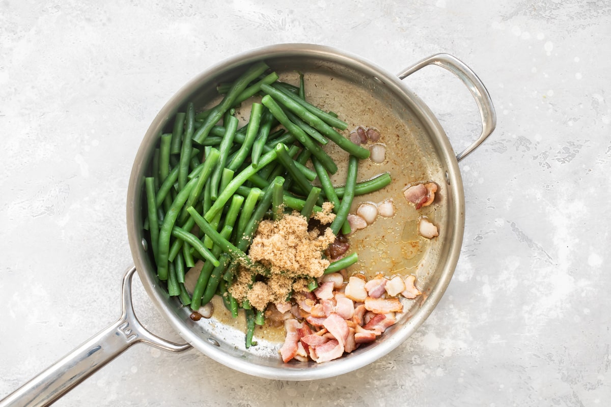 Green beans, brown sugar, and bacon in a skillet.