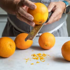 Five oranges on a countertop that have been zested.