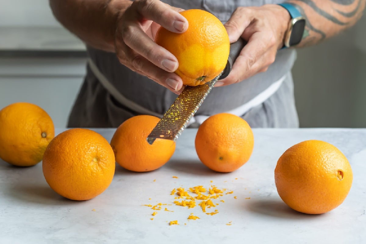 Five oranges on a countertop that have been zested.
