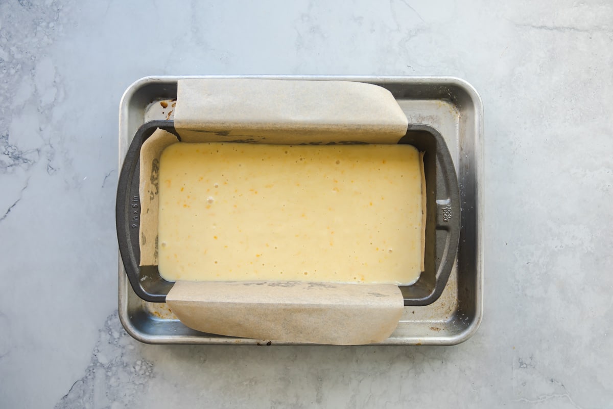 Orange cake batter in a loaf pan unbaked.