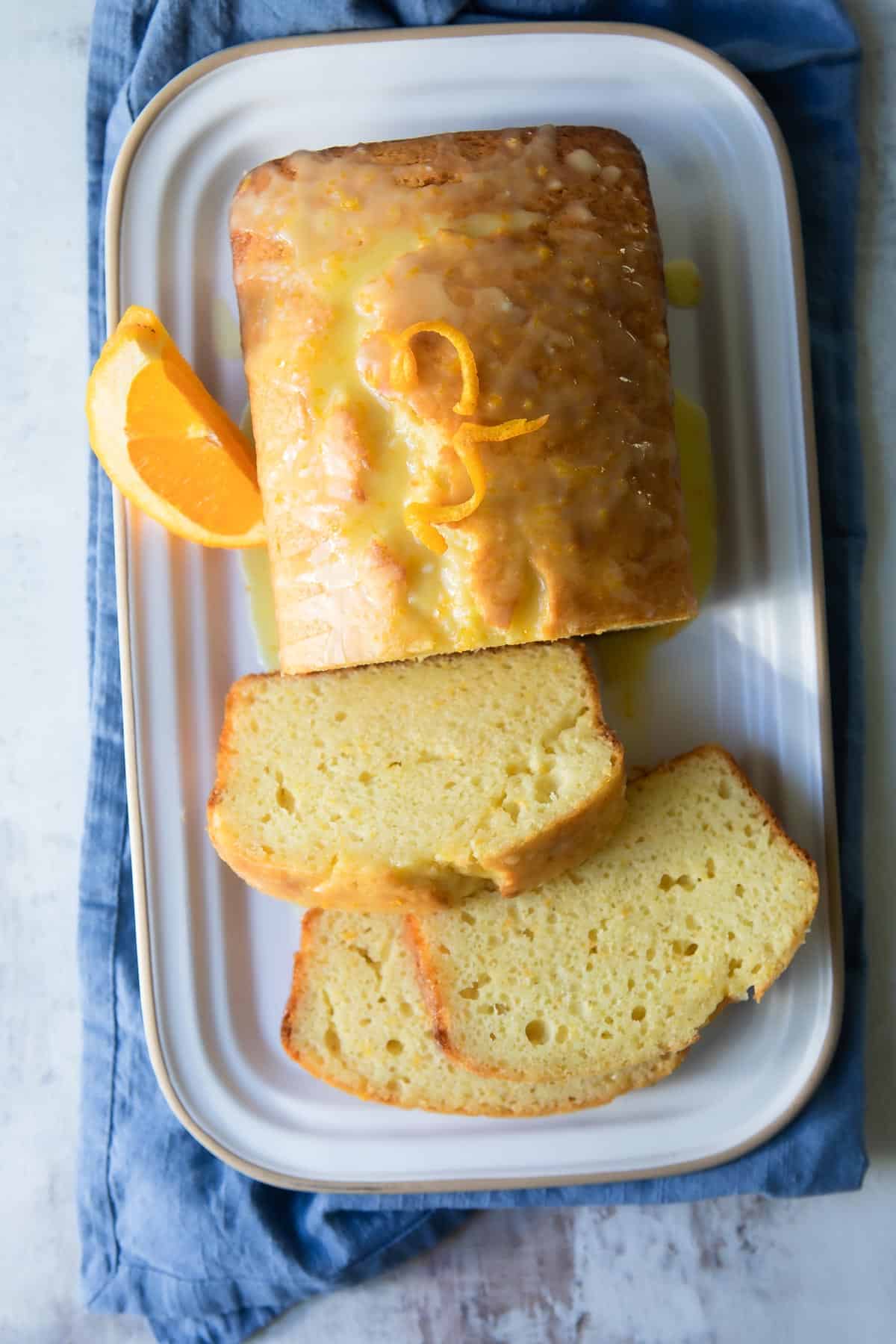 A fully baked orange loaf cake with slices cut off.