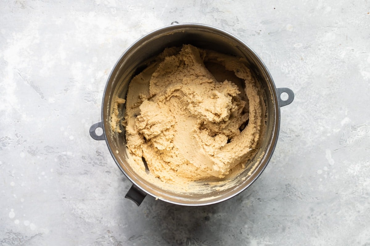 Peanut butter cookie dough in a silver mixing bowl.