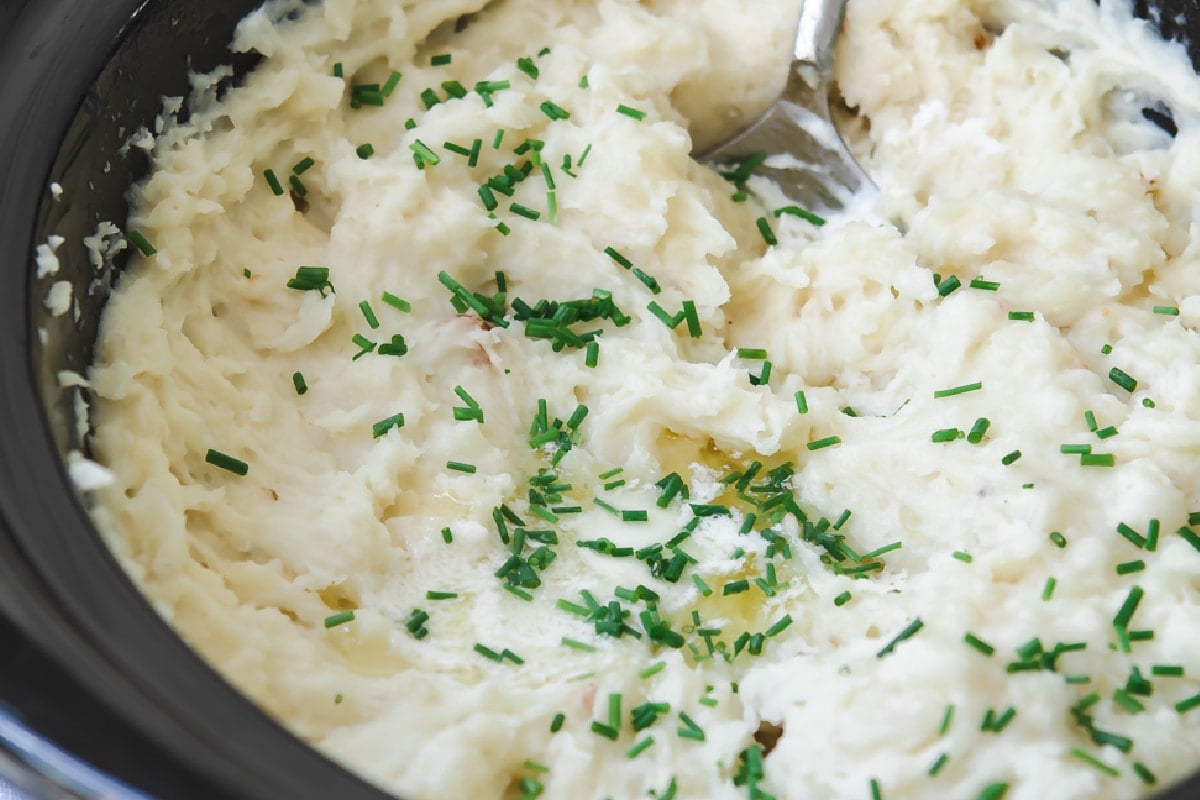 Slow cooker mashed potatoes with chives on top.