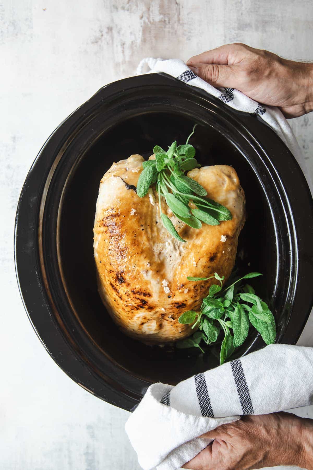 A cooked turkey breast in a crockpot.