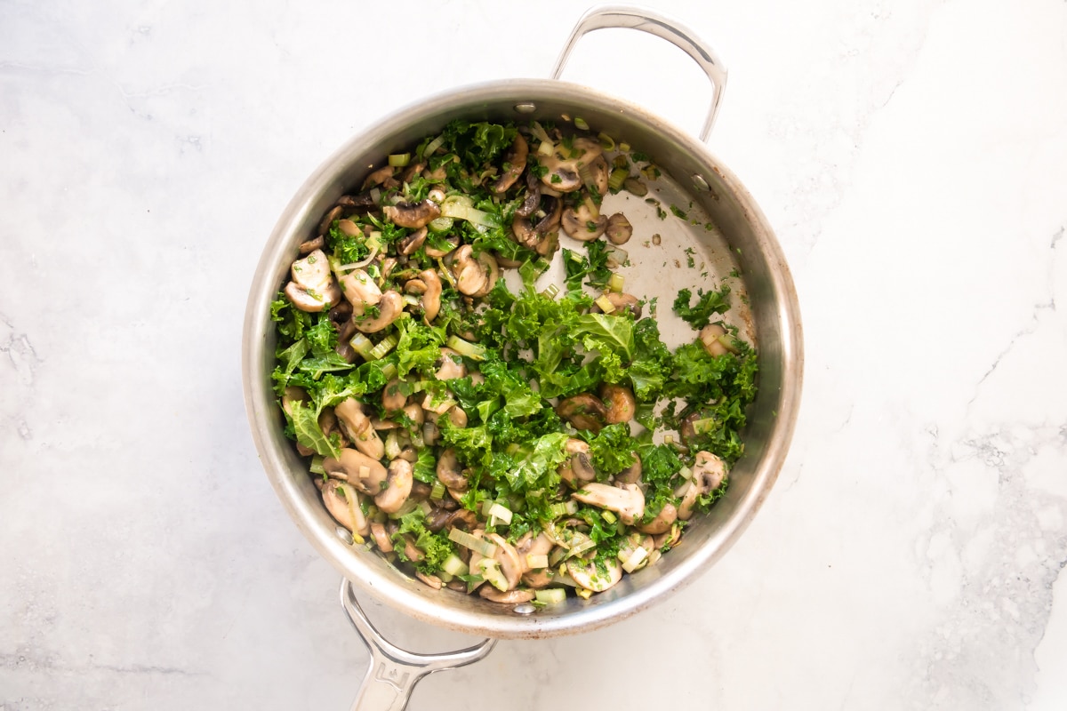 A silver skillet with vegetables in it.