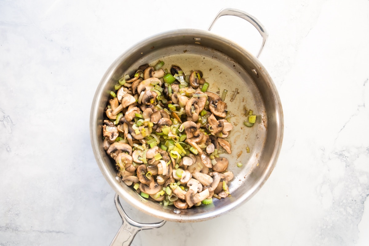 A silver skillet with vegetables in it.