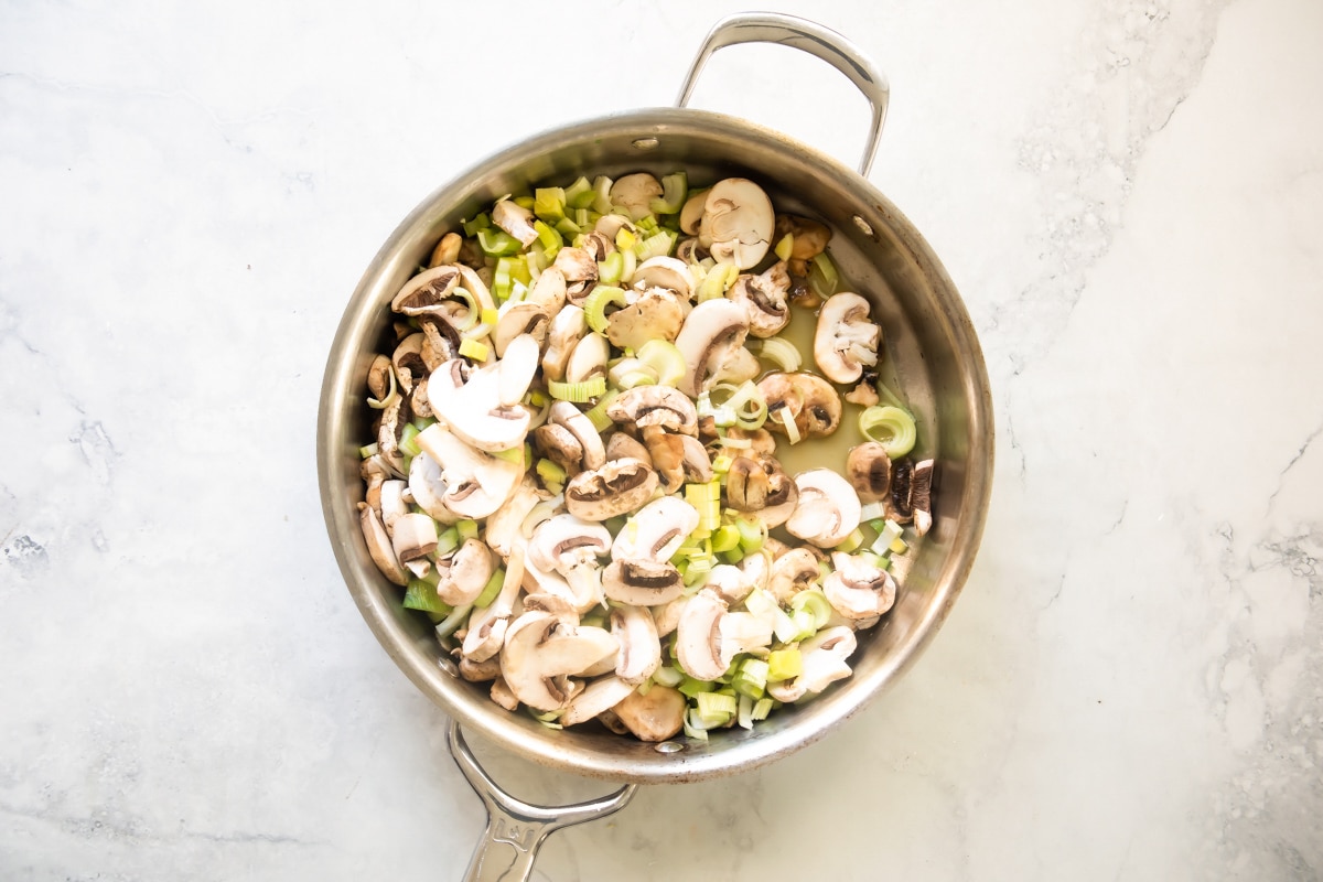 A silver skillet with vegetables in it.