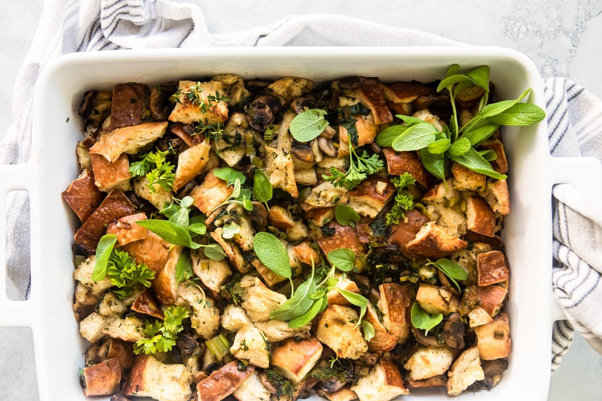A casserole dish with vegan stuffing resting on a dish towel.