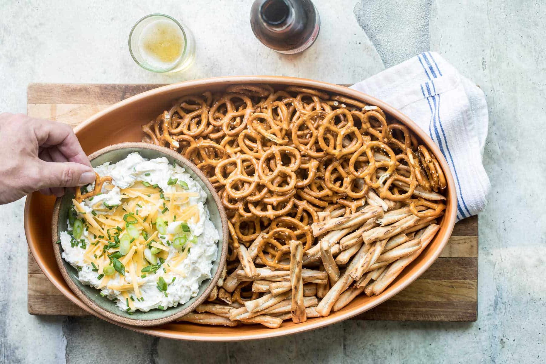 Someone dipping a pretzel in beer cheese dip.