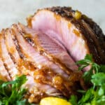 A baked ham on a platter with lemons.