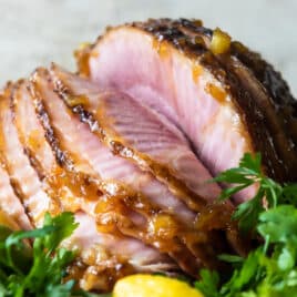 A baked ham on a platter with lemons.