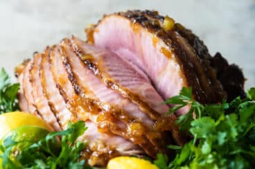 A baked ham on a platter with lemons.