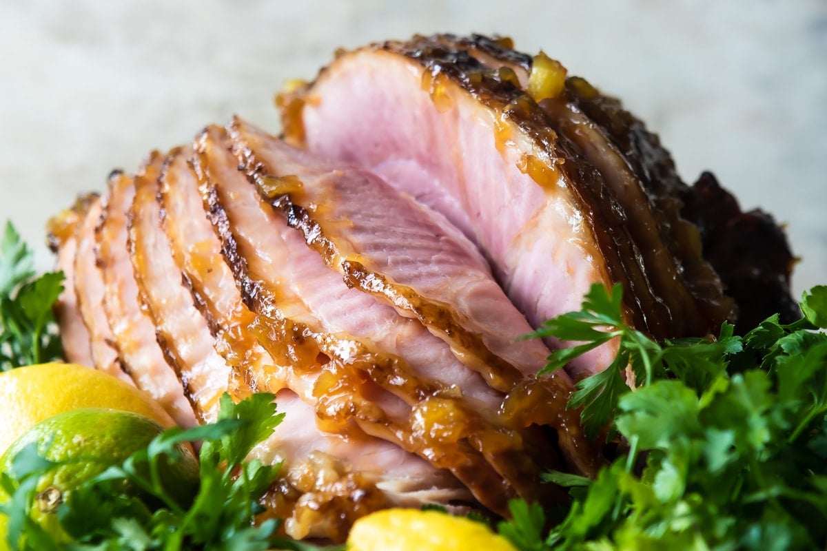 A baked ham on a platter with lemons.