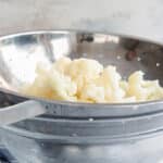 Blanched cauliflower in a colander.