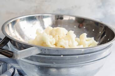 Blanched cauliflower in a colander.