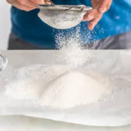 Flour being sifted onto parchment paper.