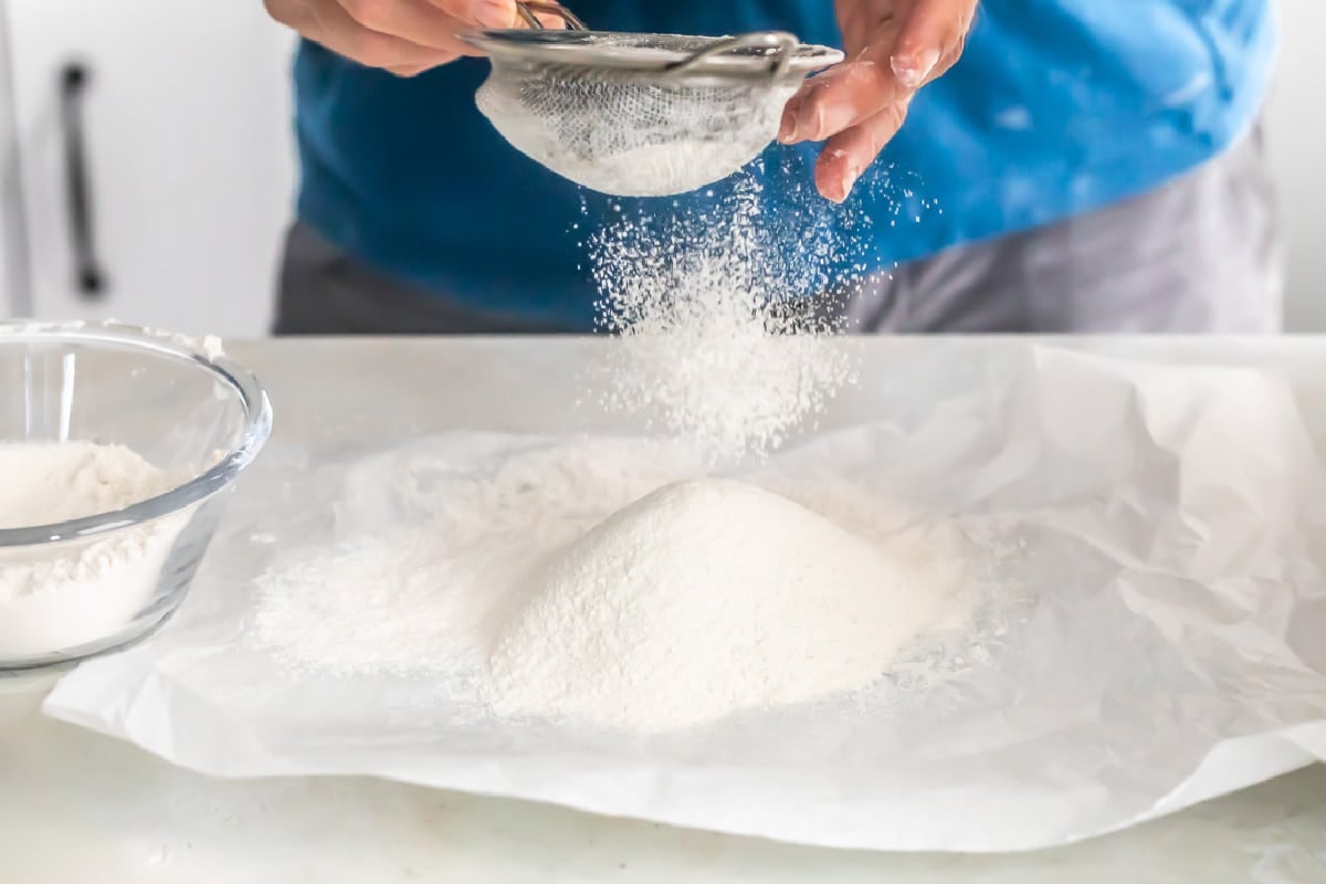 Flour being sifted onto parchment paper.