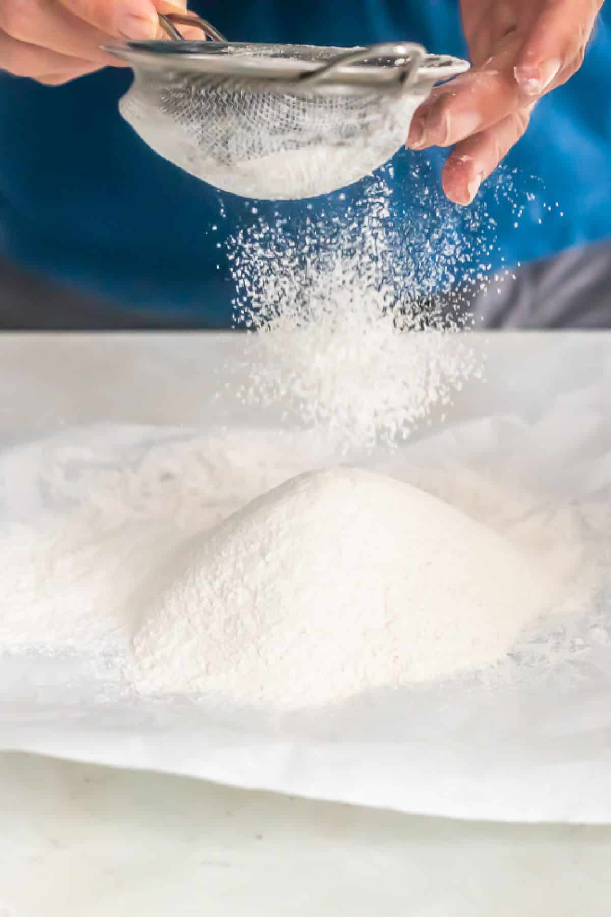 Flour being sifted onto parchment paper.