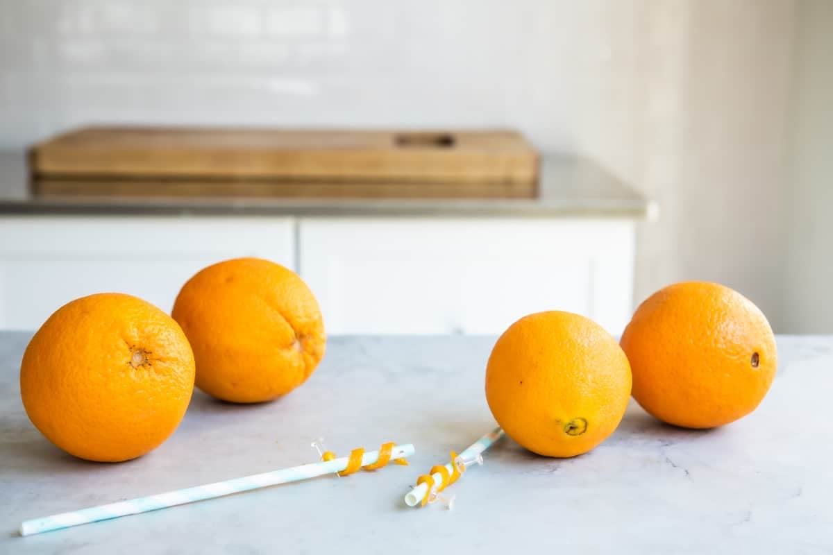 Twisting orange peel around a straw to make an orange twist.