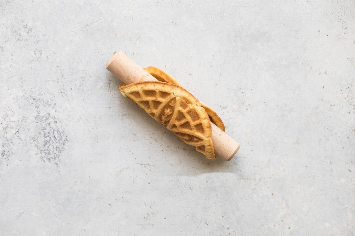 Rolling a pizzelle cookie around a dowel.