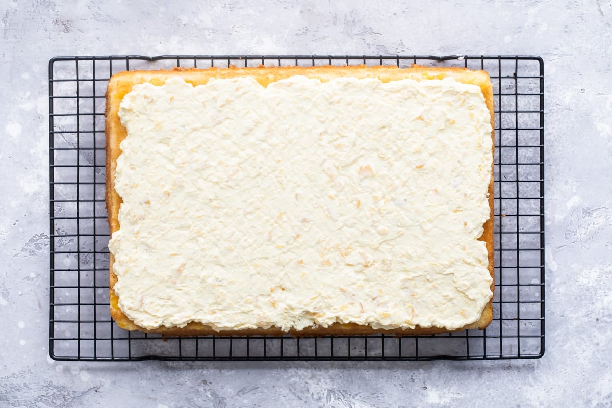 A frosted Pig Pickin' Cake on a black cooling rack.