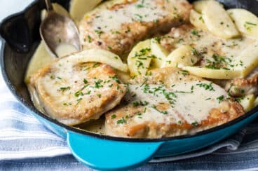 Pork Cutlets with apples in a teal skillet.