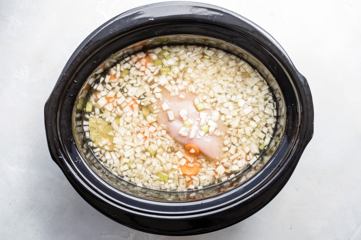 Slow cooker chicken tortellini soup cooking in a black slow cooker.