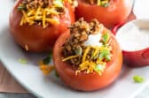 Taco stuffed tomatoes on a white platter.