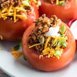 Taco stuffed tomatoes on a white platter.