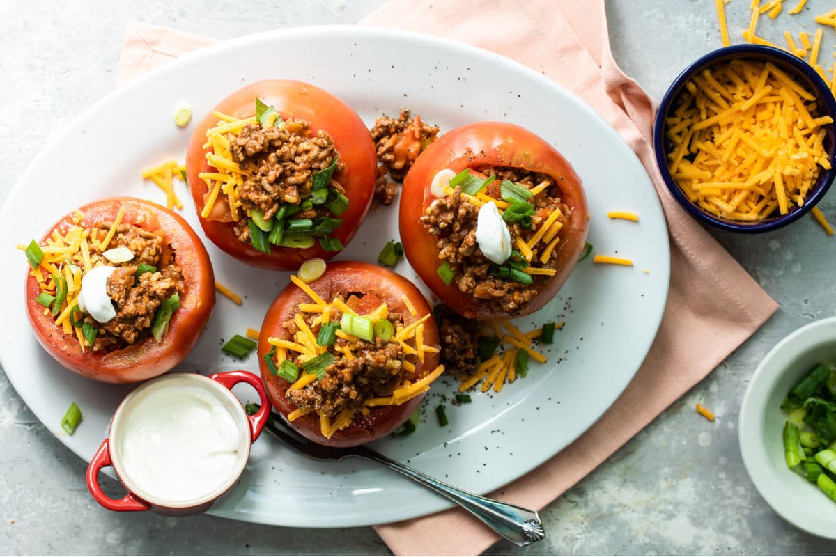 Taco stuffed tomatoes on a white platter.