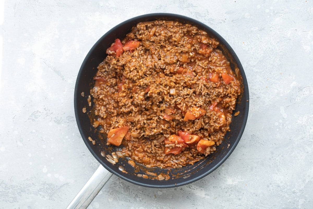 Taco stuffed tomato meat stuffing in a black skillet.
