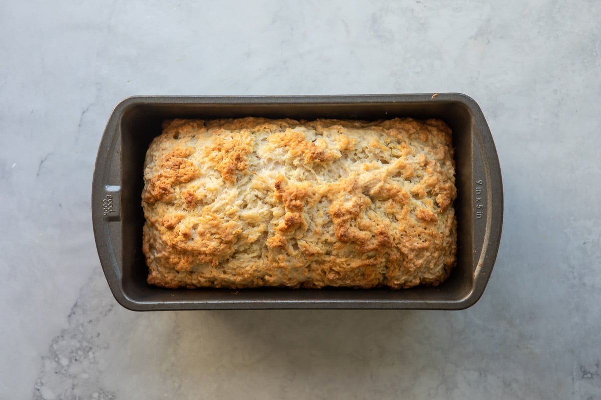 An unsliced loaf of beer bread in a bread pan.