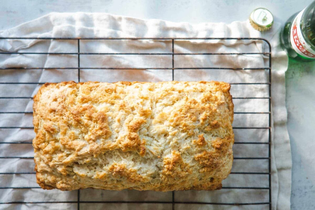 An unsliced loaf of beer bread on a cooling rack.