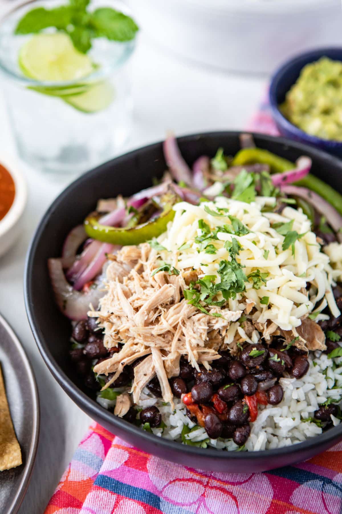 A burrito bowl filled with Chipotle copycat Carnitas, white rice, black beans, salsa, and fajita veggies.