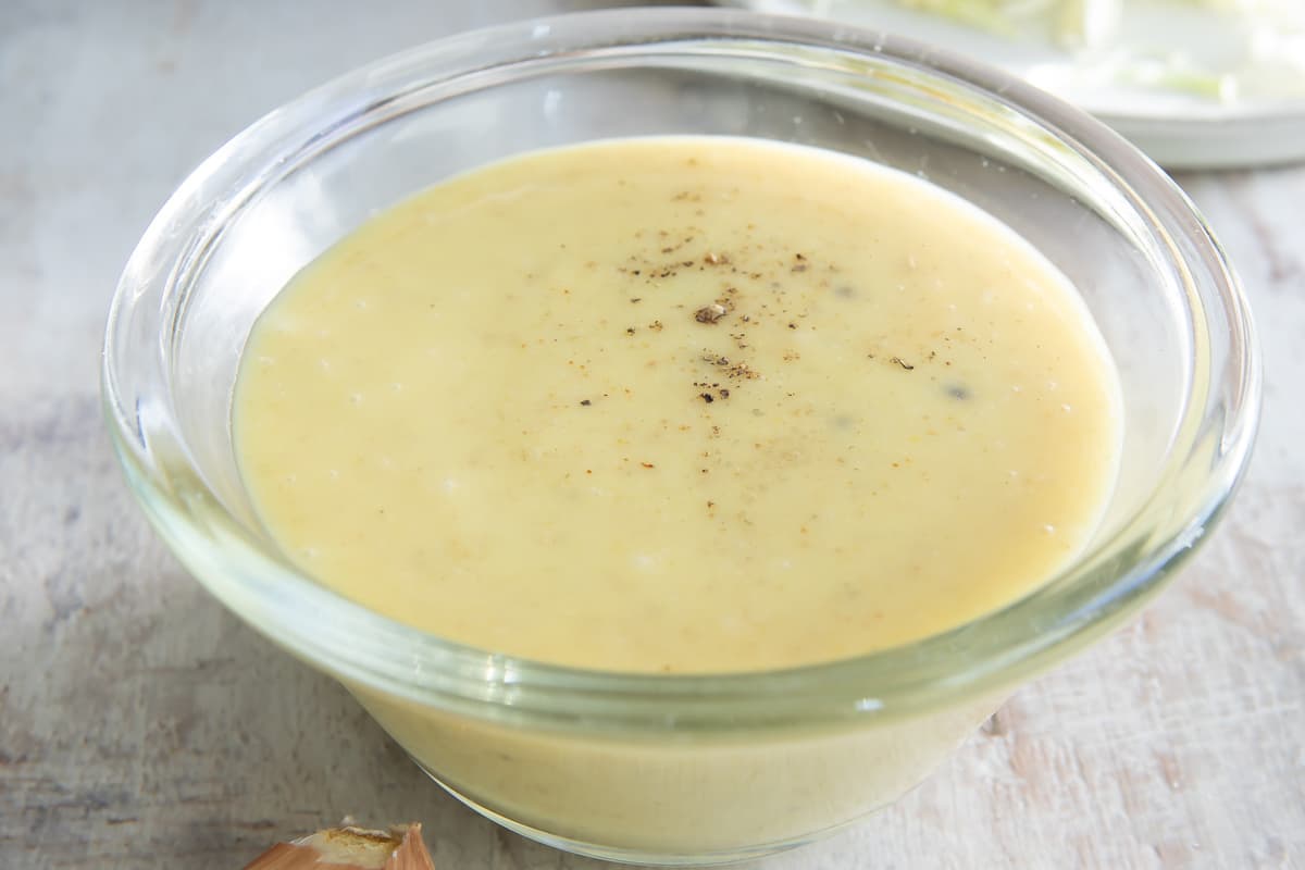 Coleslaw dressing in a clear bowl on a countertop.