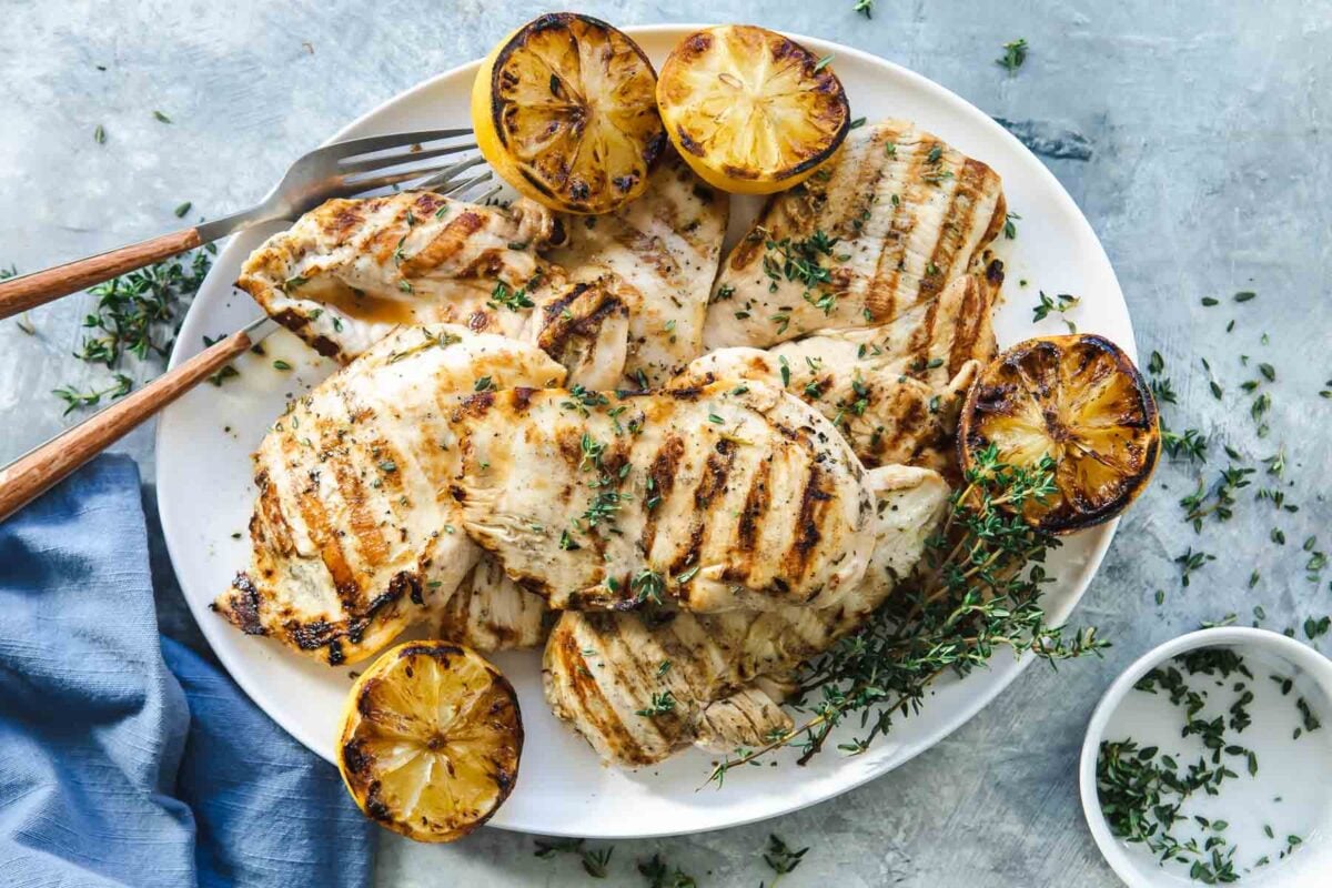 A platter full of grilled lemon chicken breasts.