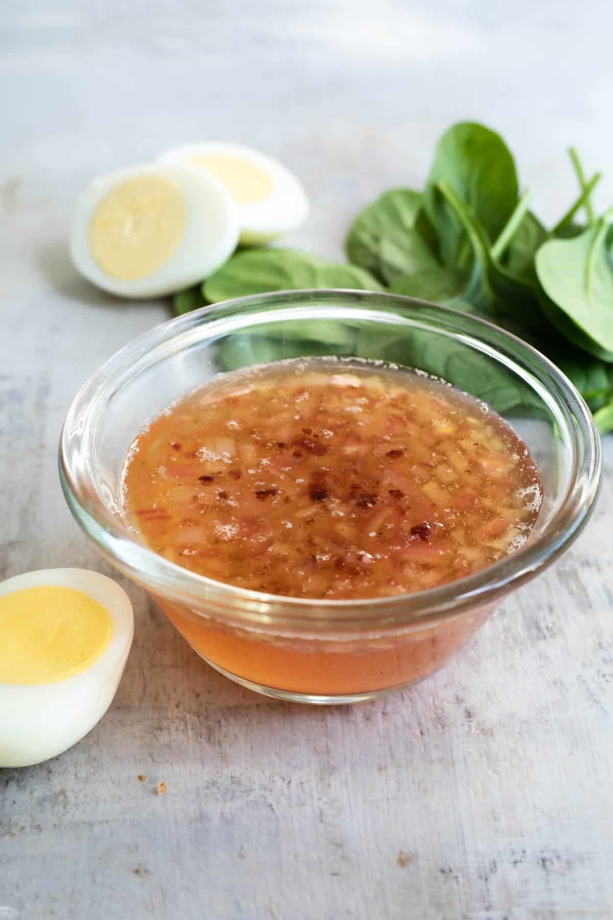 Hot bacon dressing in a clear bowl on a countertop.
