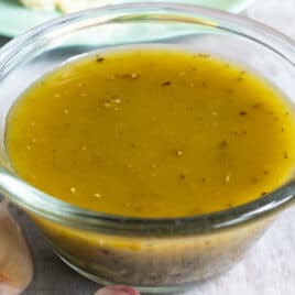 Italian dressing in a clear bowl on a countertop.
