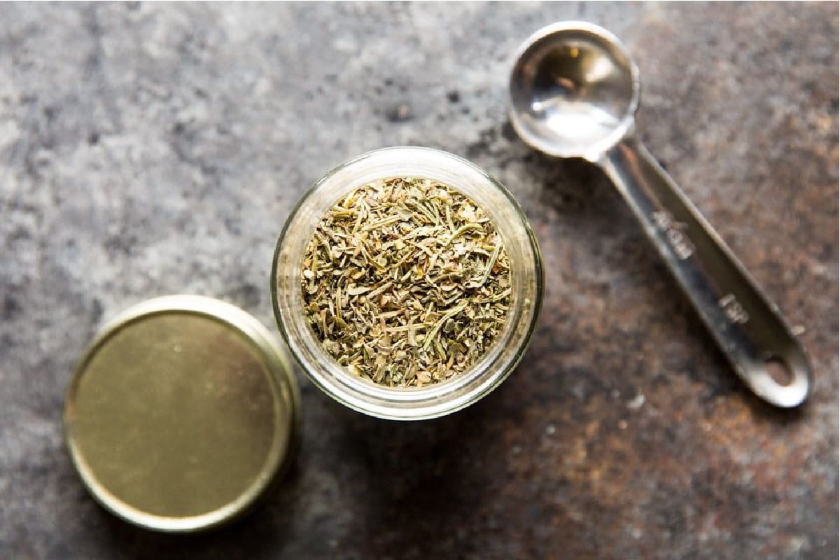 A small glass jar filled with Italian seasoning.