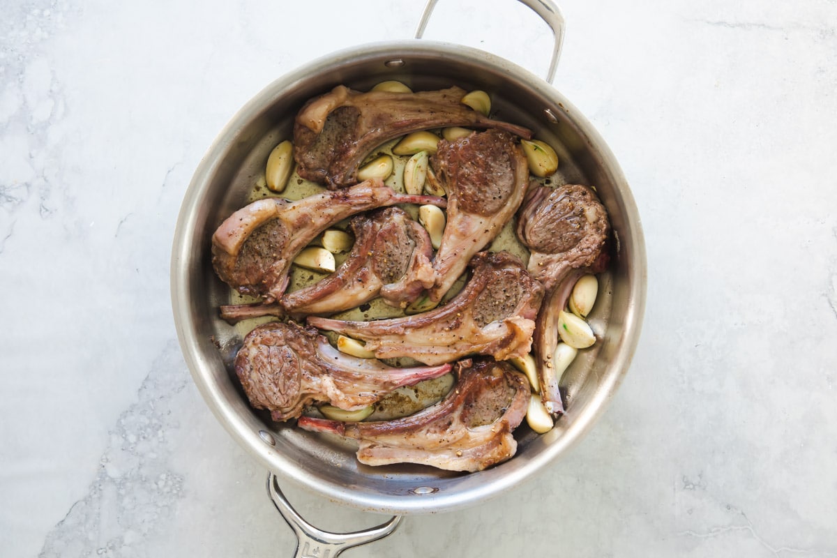 A pan of lamp chops garnished with garlic.