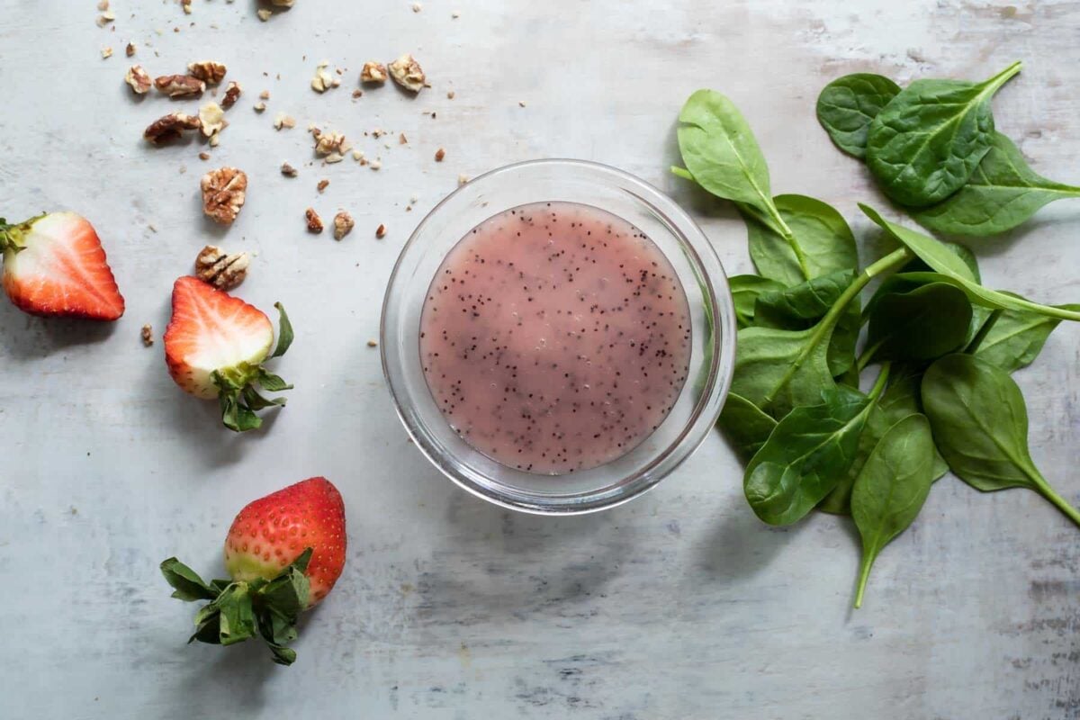 Poppyseed dressing in a clear bowl on a countertop.
