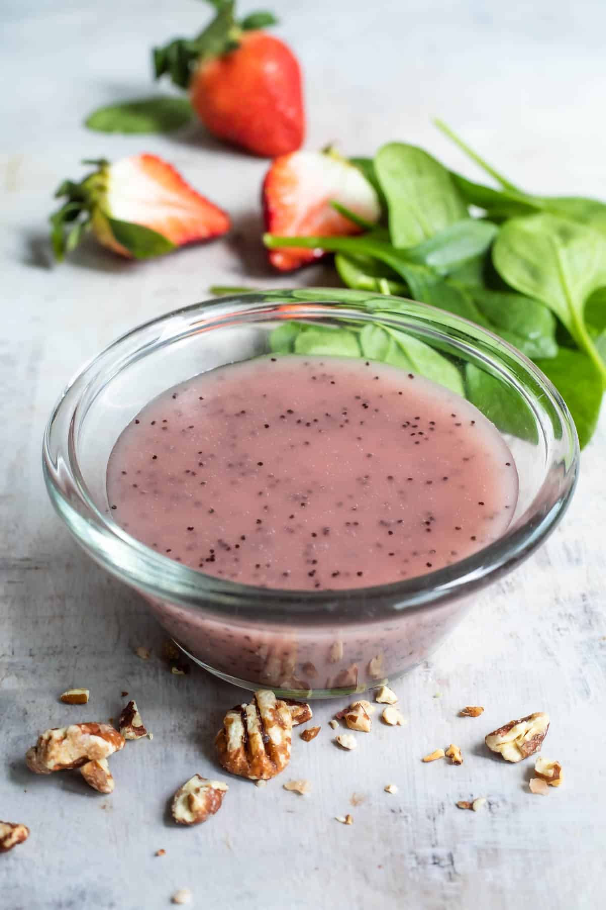 Poppyseed dressing in a clear bowl on a countertop.