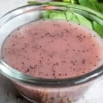 Poppyseed dressing in a clear bowl on a countertop.