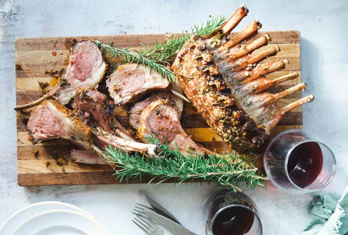Roast rack of lamb on a cutting board.
