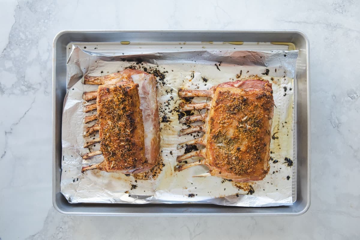 2 roasted racks of lamb on a baking sheet.