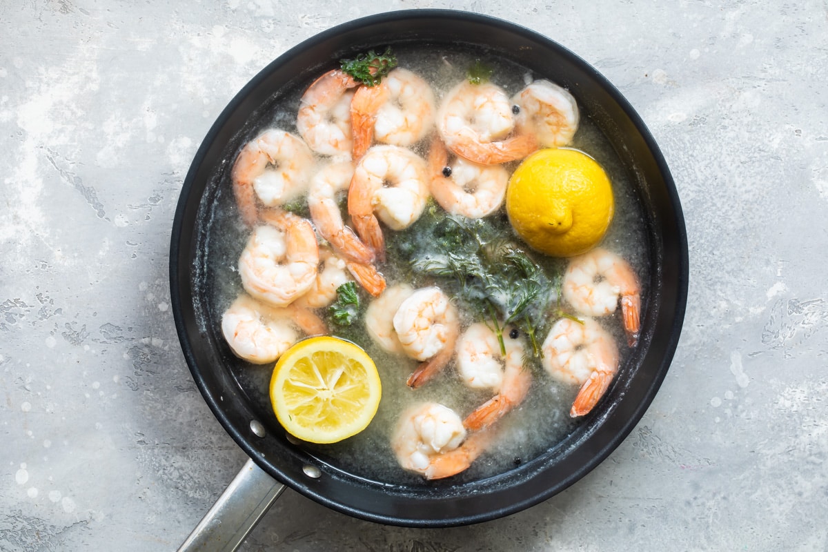 Shrimp being cooked in a black skillet.