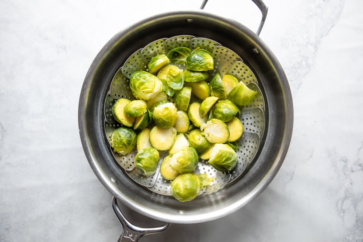 Brussels sprouts steaming in a steamer basket.